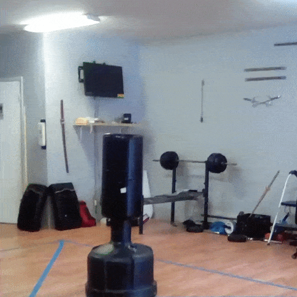 A karate student performing a jumpkick over a heavy bag